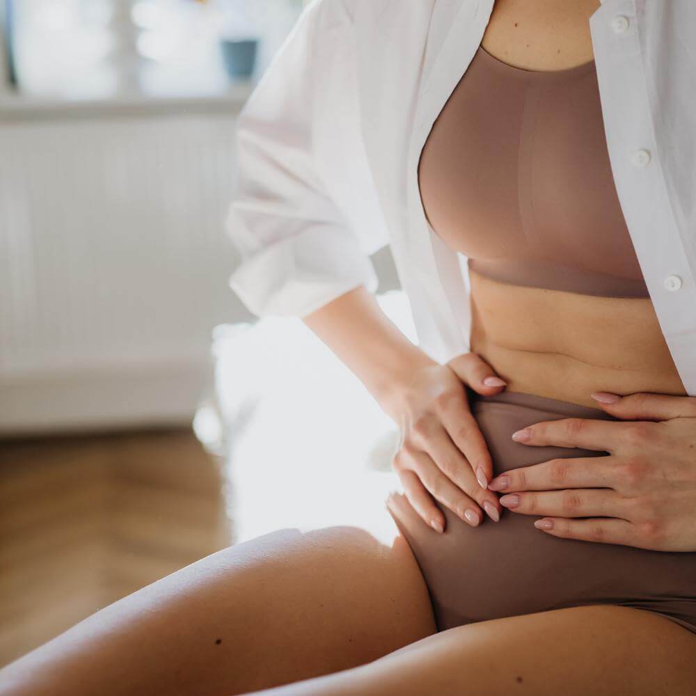 Woman resting her hands on her lower abdomen, symbolizing pelvic floor awareness
